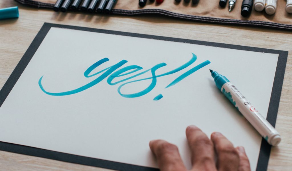 Hipster young illustrator artist in black simple tshirt creates authentic and unique hand lettering drawing in his bright industrial studio